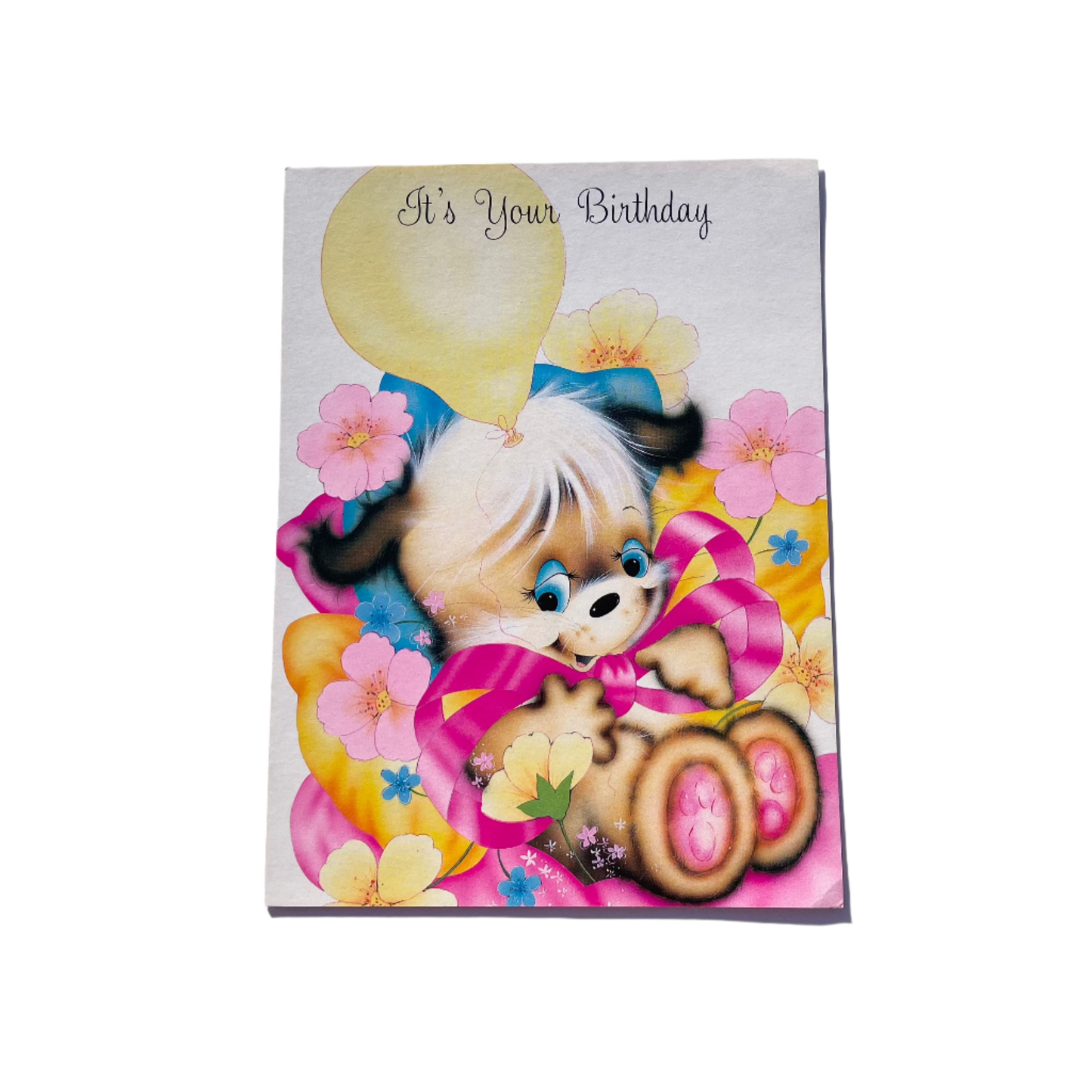 A colorful birthday card featuring a cartoon puppy with balloons and the text 'It's Your Birthday'.