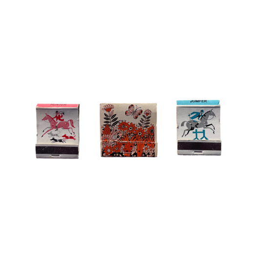 Three vintage matchbooks with visible designs laid out on a surface.