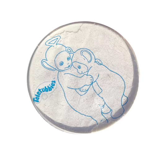 A round badge with an blue line illustration of two characters from the Teletubbies show and the logo.