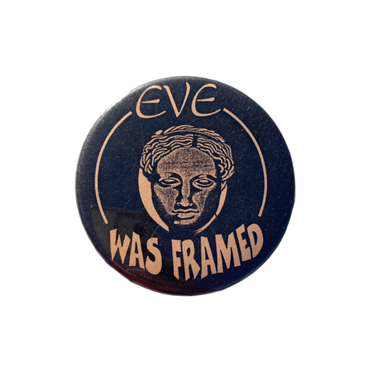 A round black badge with pale orange text , featuring the phrase 'EVE WAS FRAMED' and an illustration of a female head.