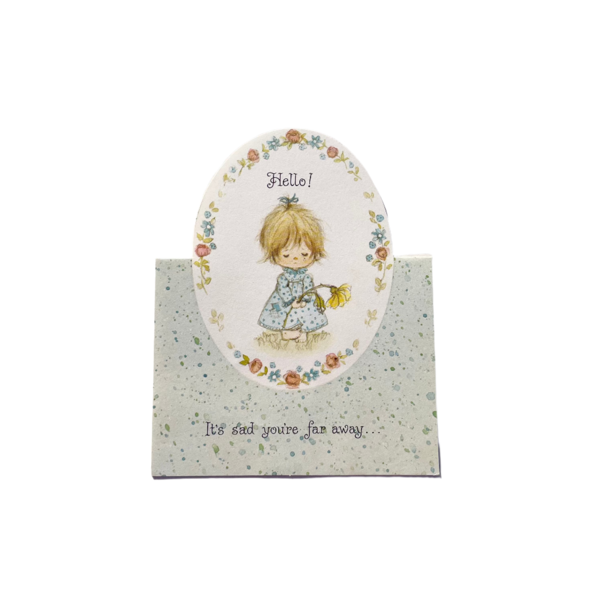 A vintage greeting card with a floral pattern and an illustration of a girl holding a flower saying 'Hello! It's sad you're far away.'