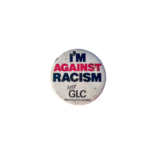 A round badge with the text 'I'M AGAINST RACISM' in black and red letters, with a smaller text 'keep GLC Working for London' in black on a white background.